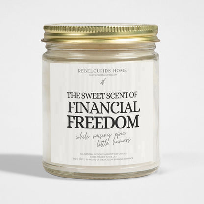 A white candle with a label that reads 'THE SWEET SCENT OF FINANCIAL FREEDOM', with a gold lid on the side.