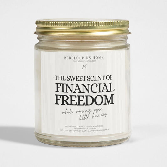 A white candle with a label that reads 'THE SWEET SCENT OF FINANCIAL FREEDOM', with a gold lid on the side.
