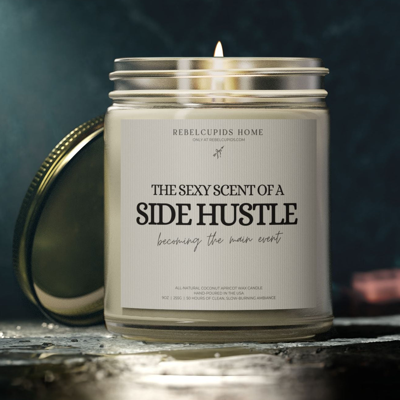 Candle with a label reading 'The Sexy Scent of a Side Hustle' on a dark background